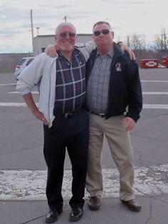 Two men posing outdoors on a cold day with snow patches visible.