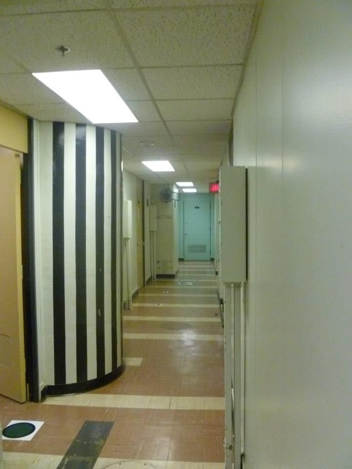 A hallway with striped black and white curved walls and a tiled floor.