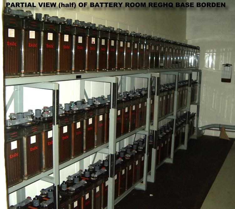 Battery room with multiple large batteries arranged on shelves.