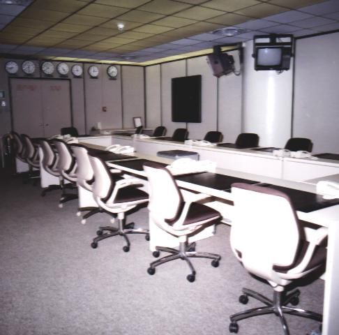 Modern conference room with white chairs and a long table under ceiling lights.