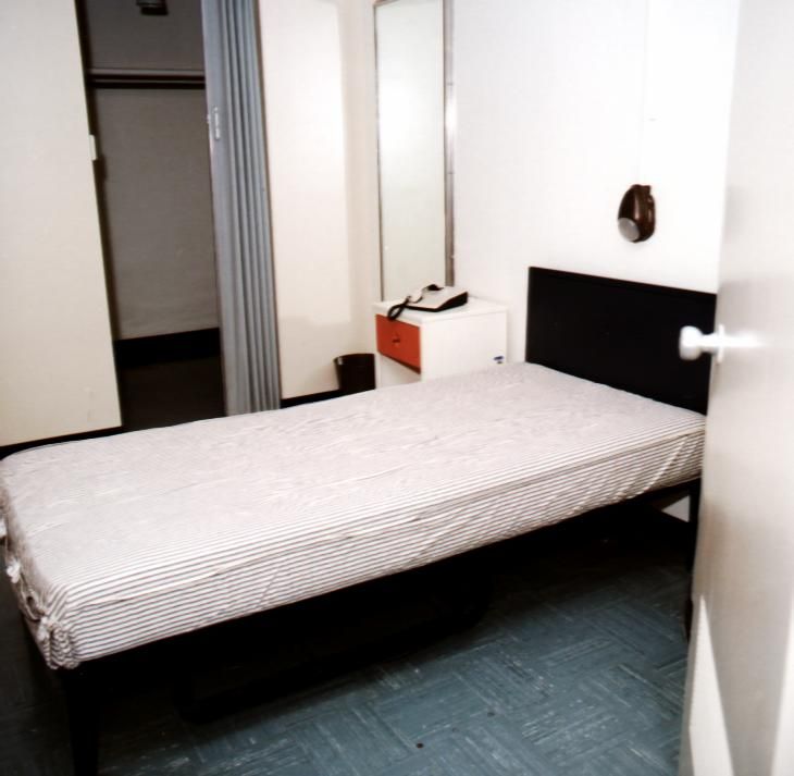 Minimalist bedroom with a single bed and white walls.
