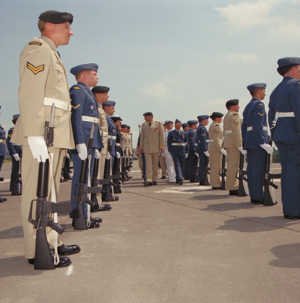 Military personnel standing in formation during a formal inspection.