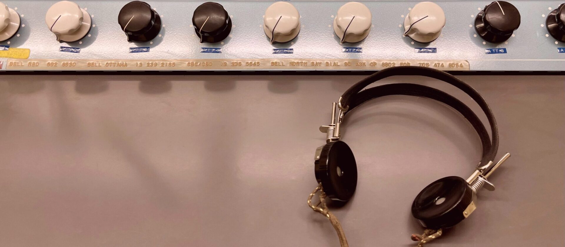 Retro headphones hanging beside vintage audio control knobs.