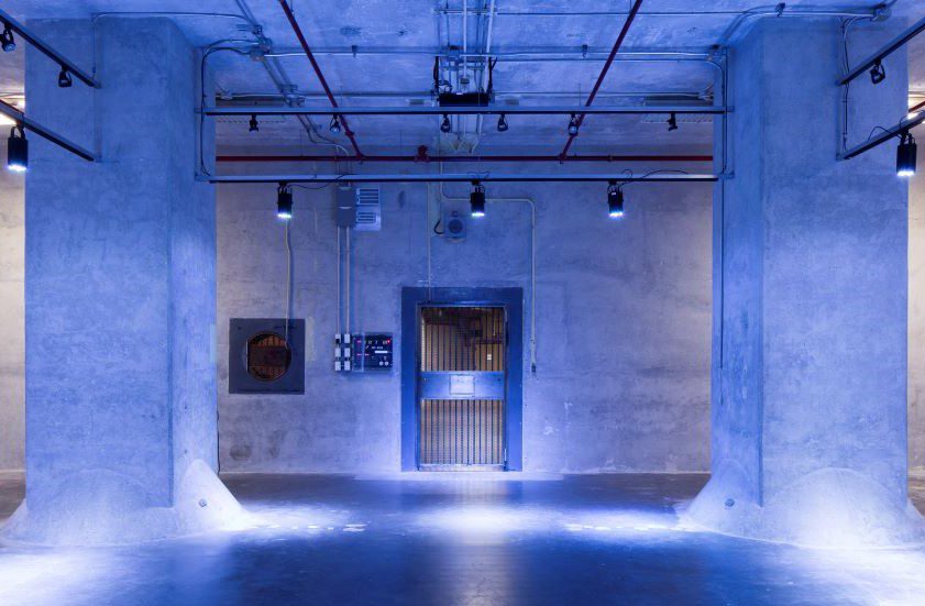 Futuristic room with blue lighting and a central metallic door.