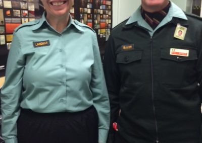 Two people in uniform standing side by side, smiling.