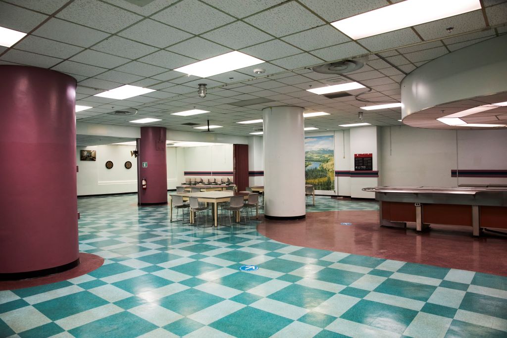 Empty cafeteria with checkered blue and white floor tiles and tables.