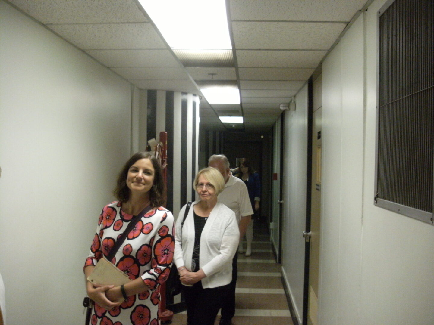 Group of people smiling in a hallway.