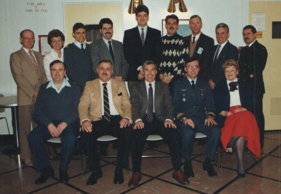 A group of men and women gathered for a formal photo indoors.