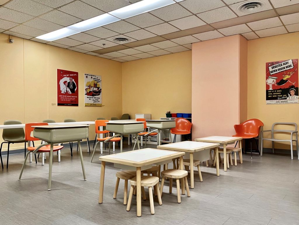 A colorful classroom with small wooden tables and chairs.