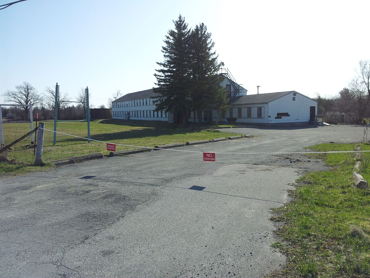 Empty paved area with a small sign and buildings in the background.
