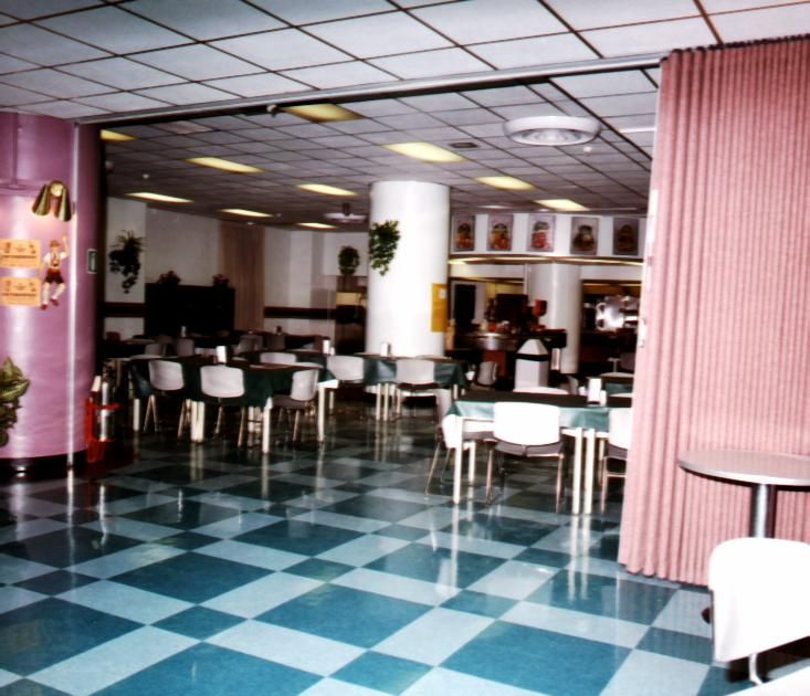Empty cafeteria with checkerboard floor and pink curtains.