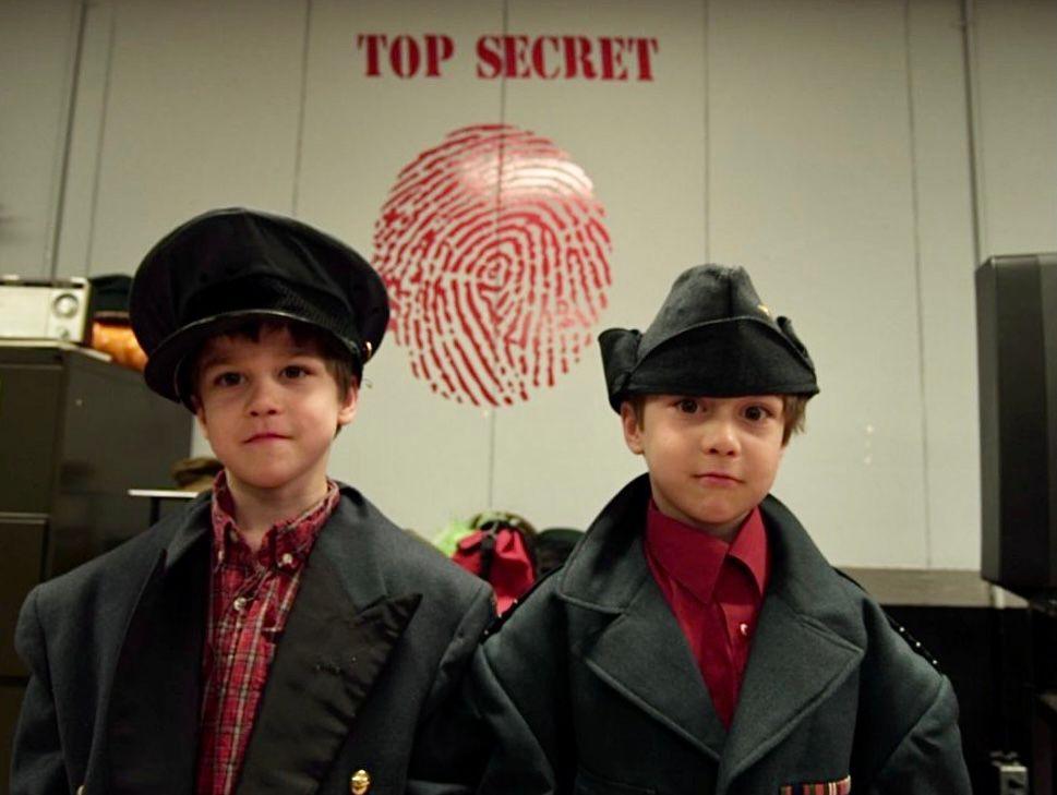 Two boys dressed as detectives stand in front of a 'Top Secret' sign with a fingerprint.