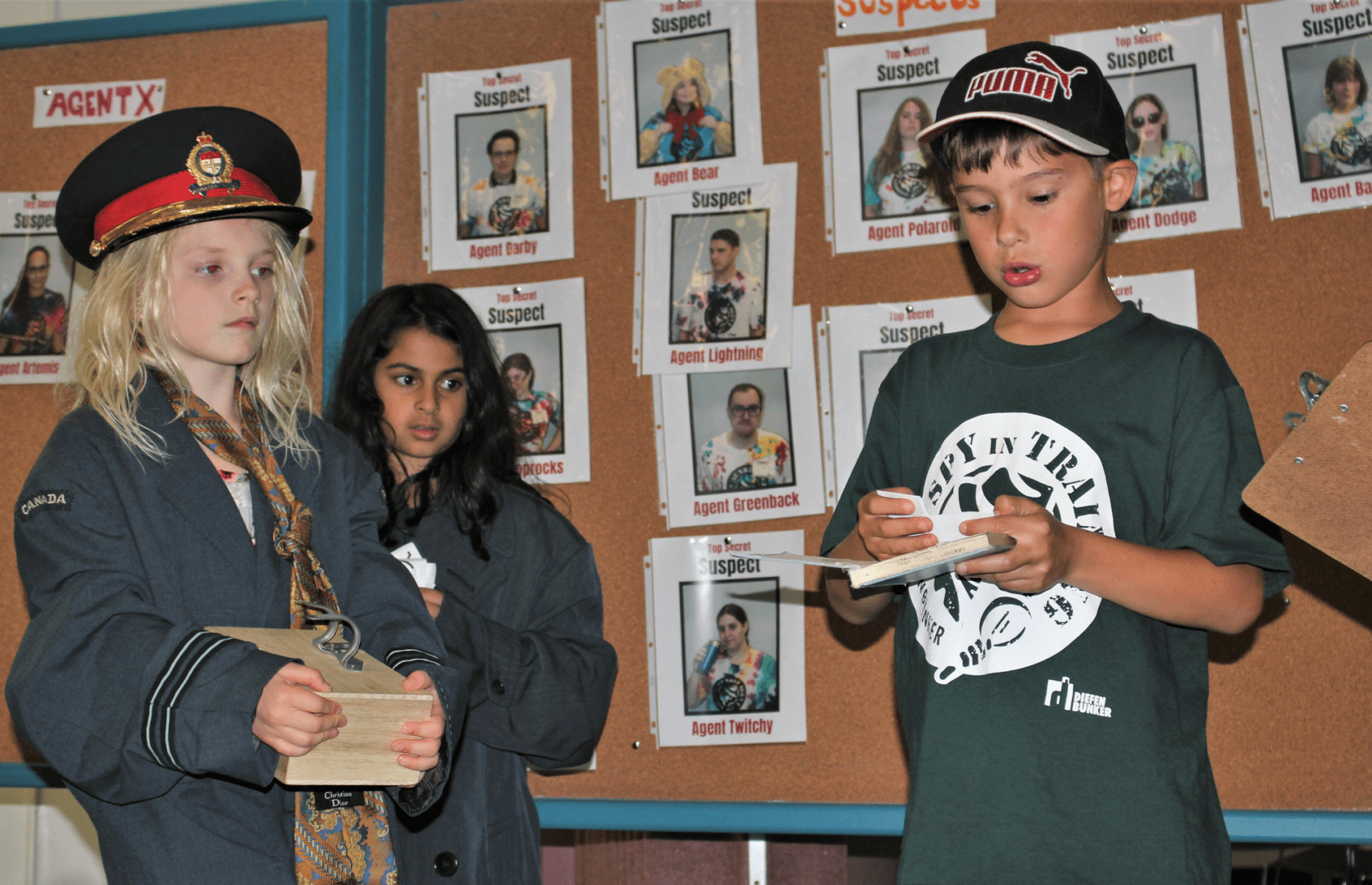 Children reading and discussing in a classroom with 'Wanted' posters on the wall.