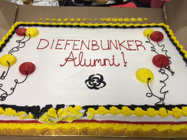 Celebratory cake for Diefenbunker Alumni with colorful balloons and yellow accents.