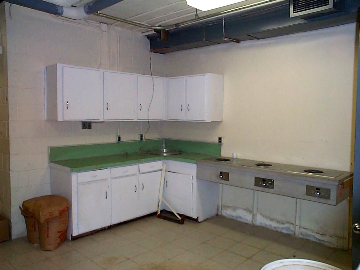 Old kitchen with white cabinets and green countertops.