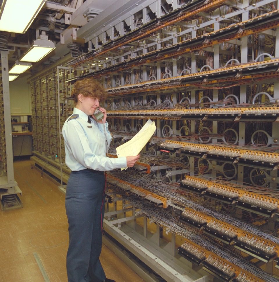 A person inspects rows of computer hardware in a large data center.