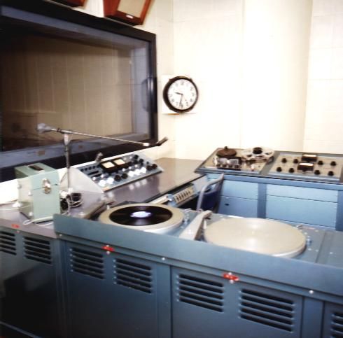 Vintage audio equipment setup with reel-to-reel tape recorders and a large TV.