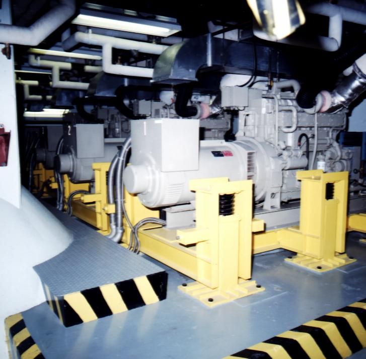 Industrial machinery secured on yellow stands in a factory setting.