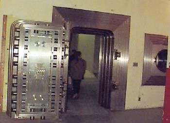 A person walking through a large metal and wooden security door.