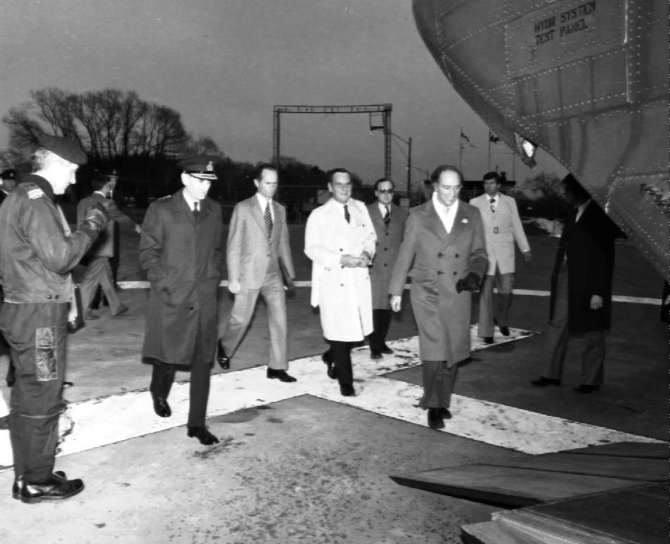 Group of men walking on an airport runway next to an airplane at night.