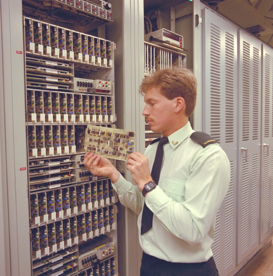 A man working on vintage computer hardware in a server room.
