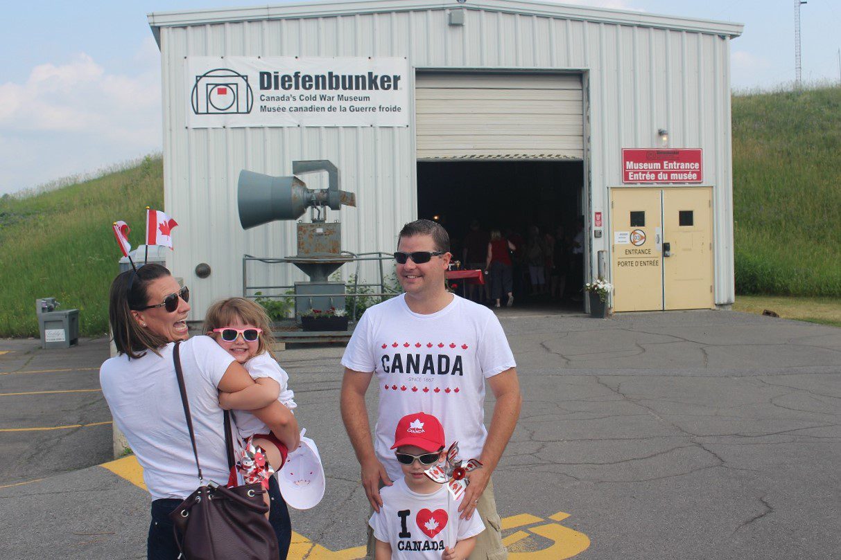 Family standing outside Diefenbunker museum entrance on a sunny day.