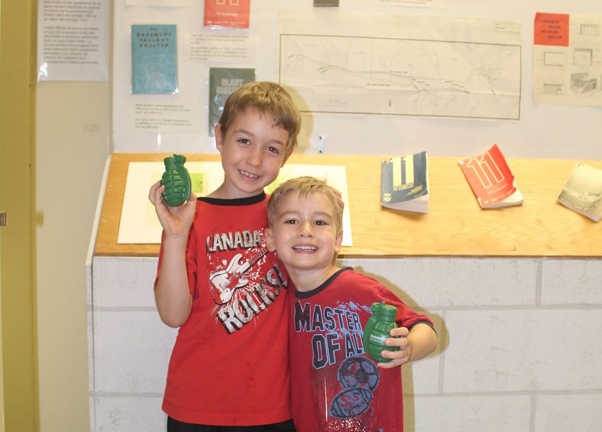 Two smiling boys posing indoors with books in the background.