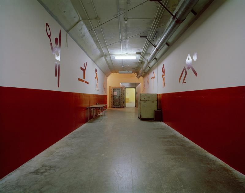 A dimly lit corridor with red and white painted walls and ceiling lights.