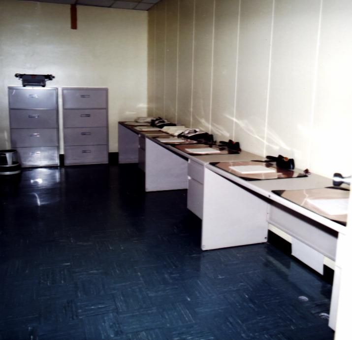A vintage computer room with multiple terminals and a filing cabinet.