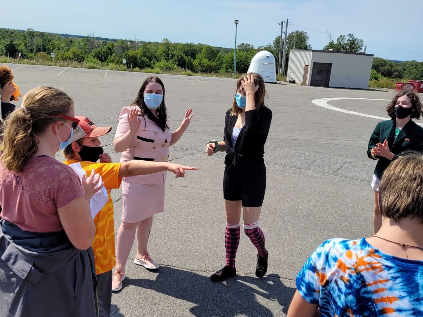 A group of women, one in a peach dress, engaged in conversation outdoors.