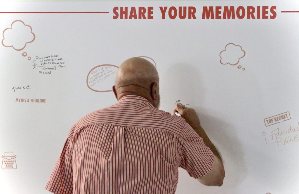 A man writes a memo on a large board with 'SHARE YOUR MEMO' header.