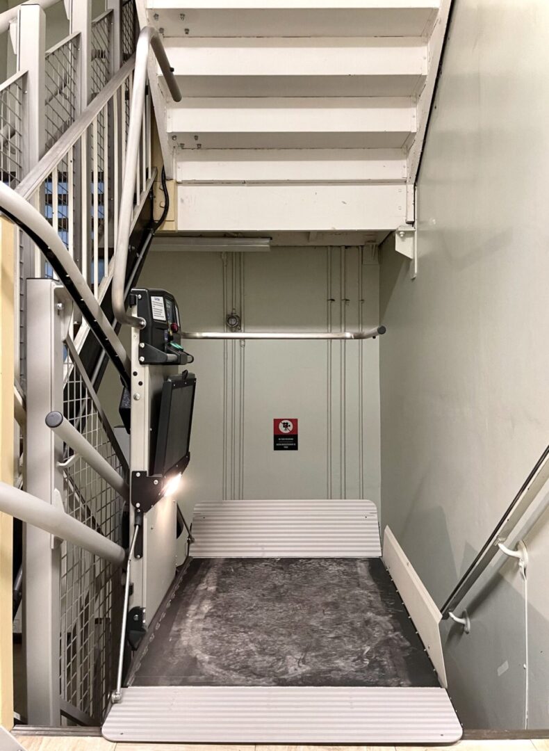 Narrow stairway leading down to a white door with a warning sign.