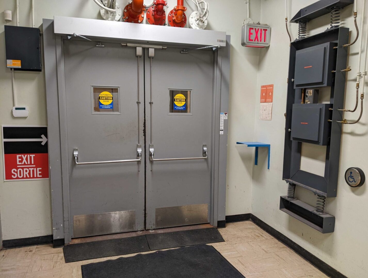 Double metal doors with warning signs in a utility room.