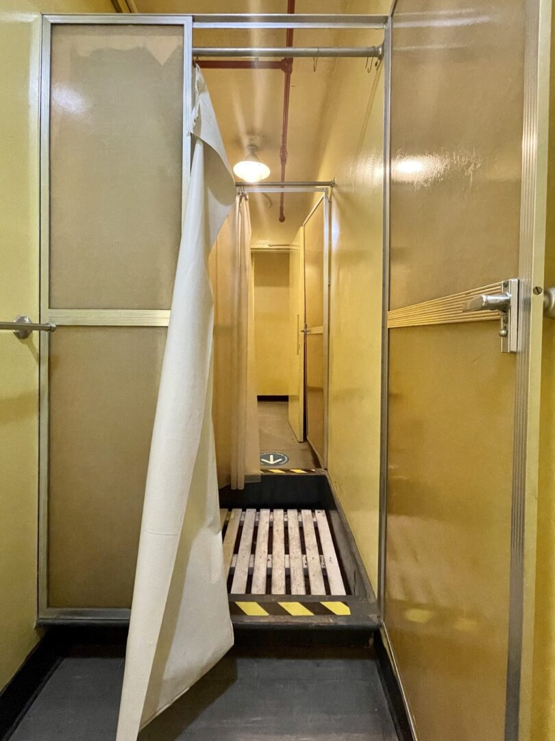 Interior of a compact, vintage train bathroom with shower and toilet.