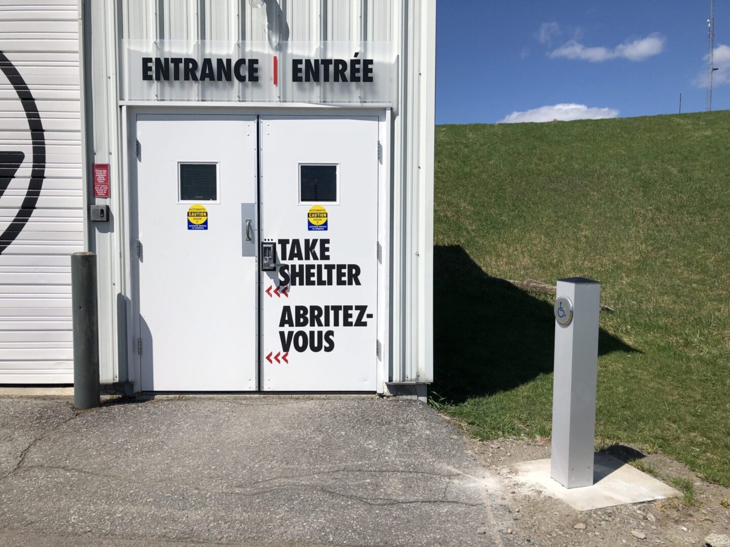 White shelter entrance doors with signs advising to "Take Shelter."