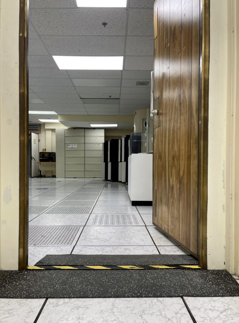 View through a door into a tiled room with wooden walls and fluorescent lighting.