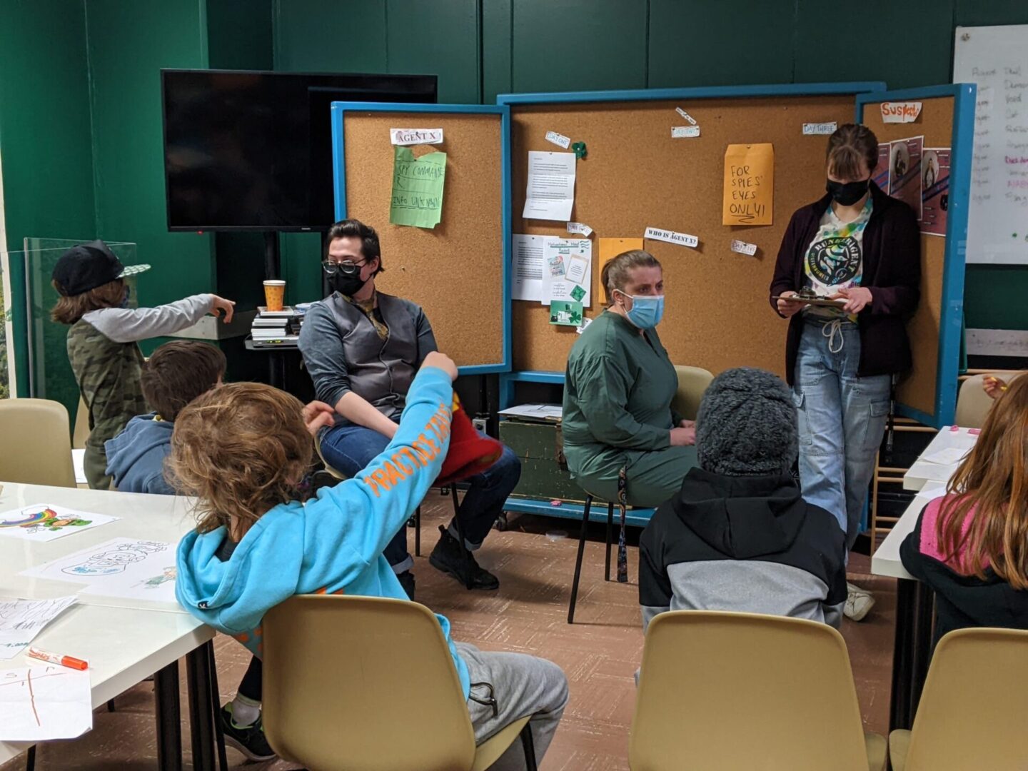 Children and adults wearing masks engage in a classroom discussion.