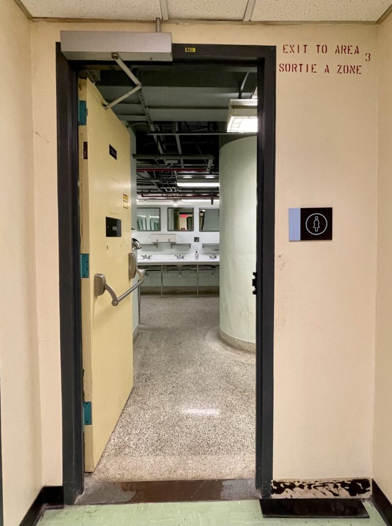 Open door revealing an industrial or mechanical room with pipes and equipment.