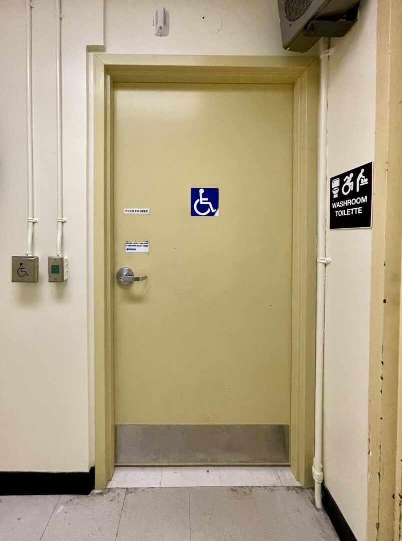 A closed beige door with a wheelchair accessibility sign in a hallway.