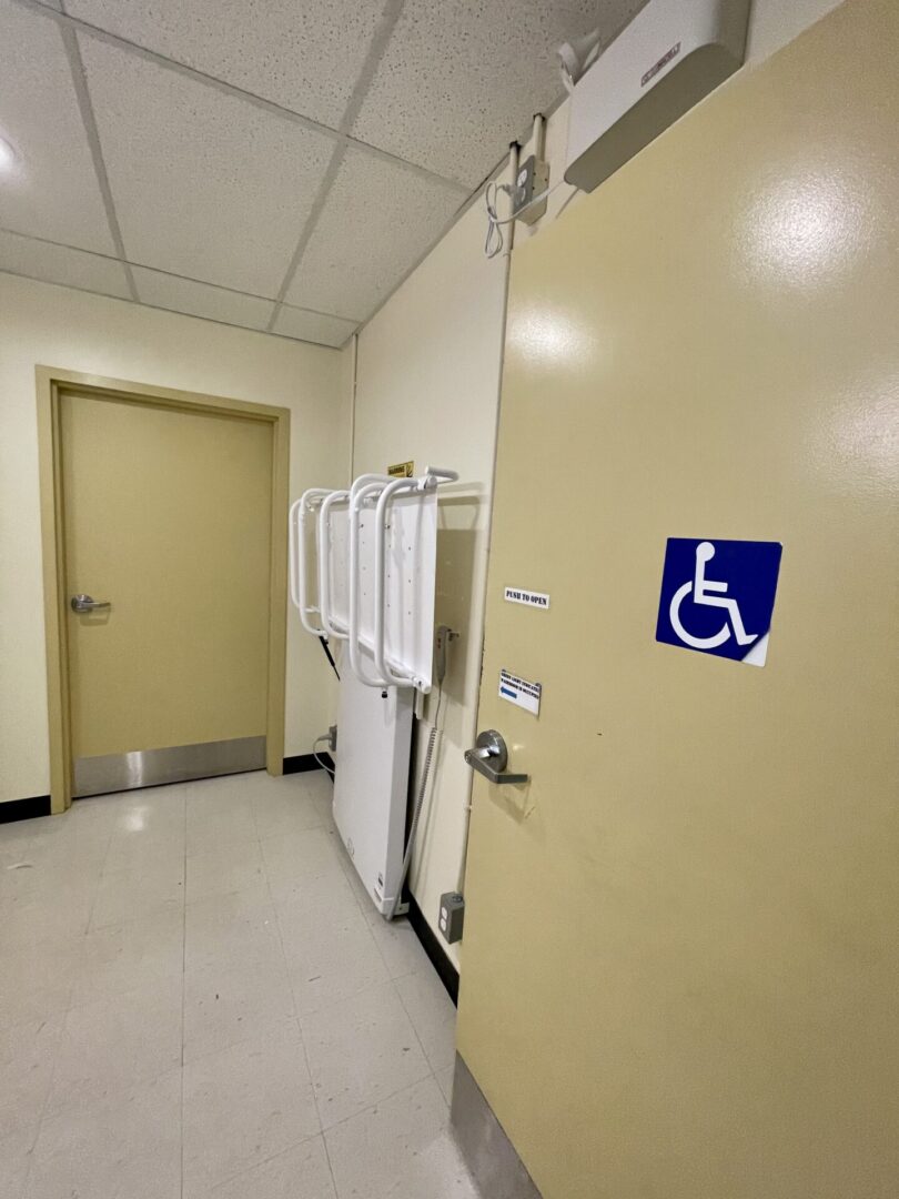 Bathroom door marked for accessibility, with urinals visible inside.