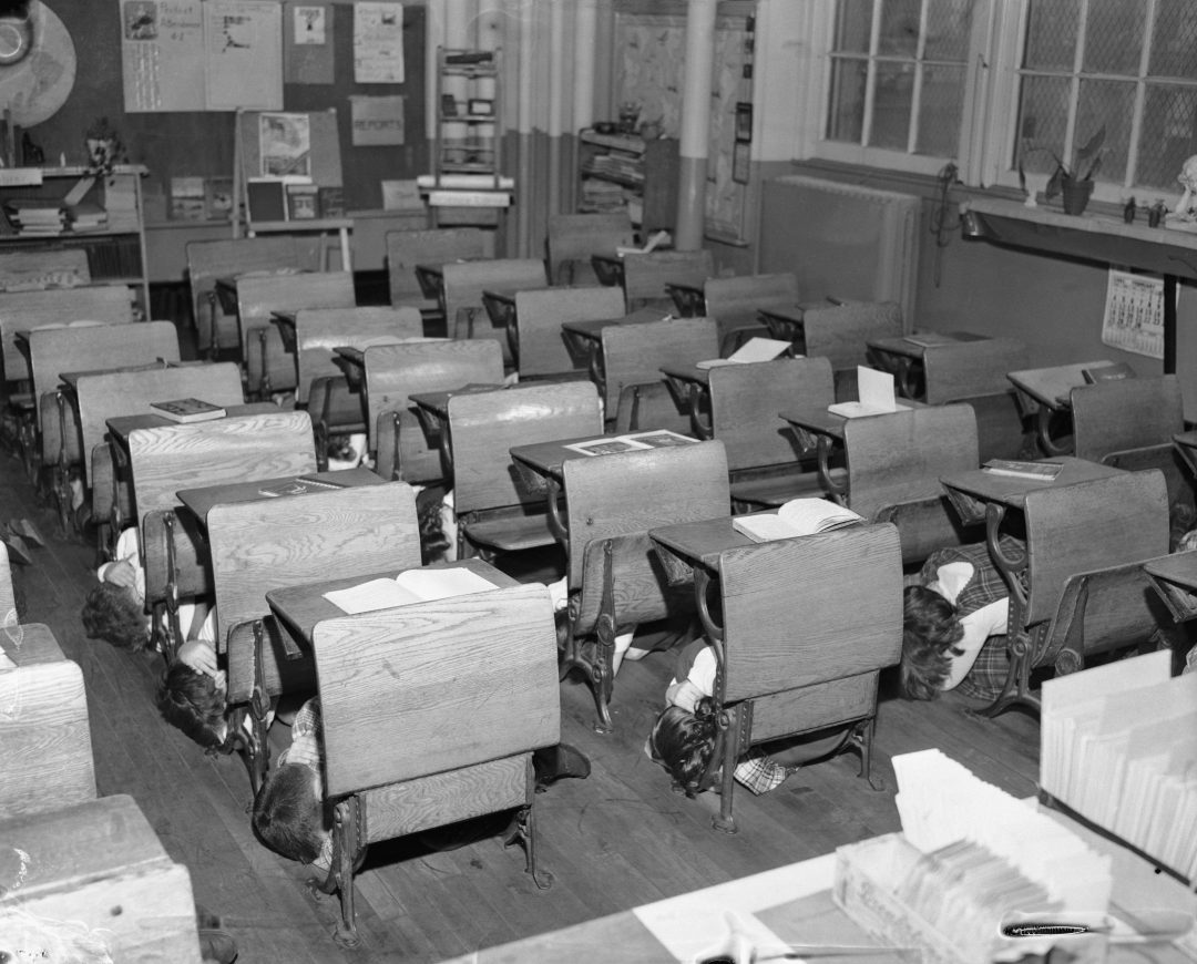 Empty vintage classroom with neatly arranged wooden desks and chairs.