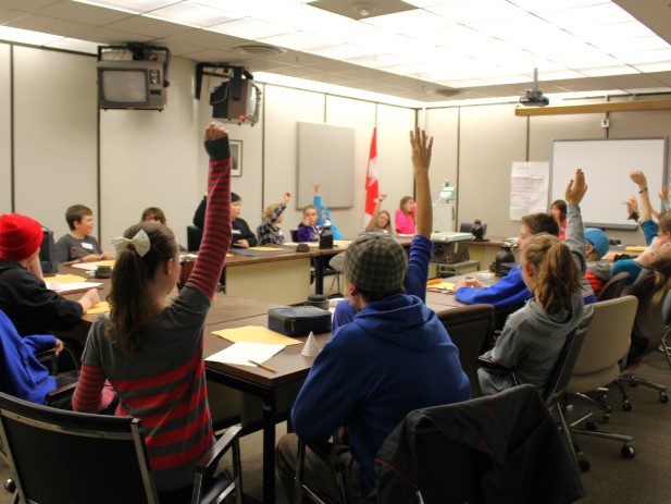 People raising hands in a meeting room during a vote.