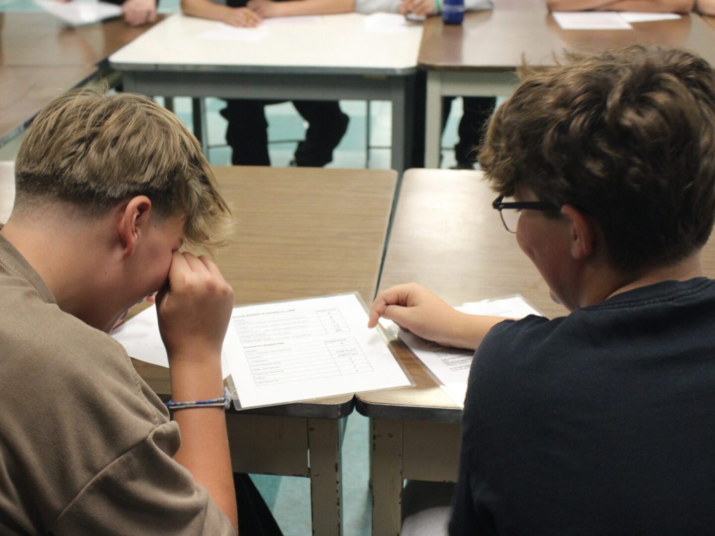 Two students working together on a worksheet at a classroom table.