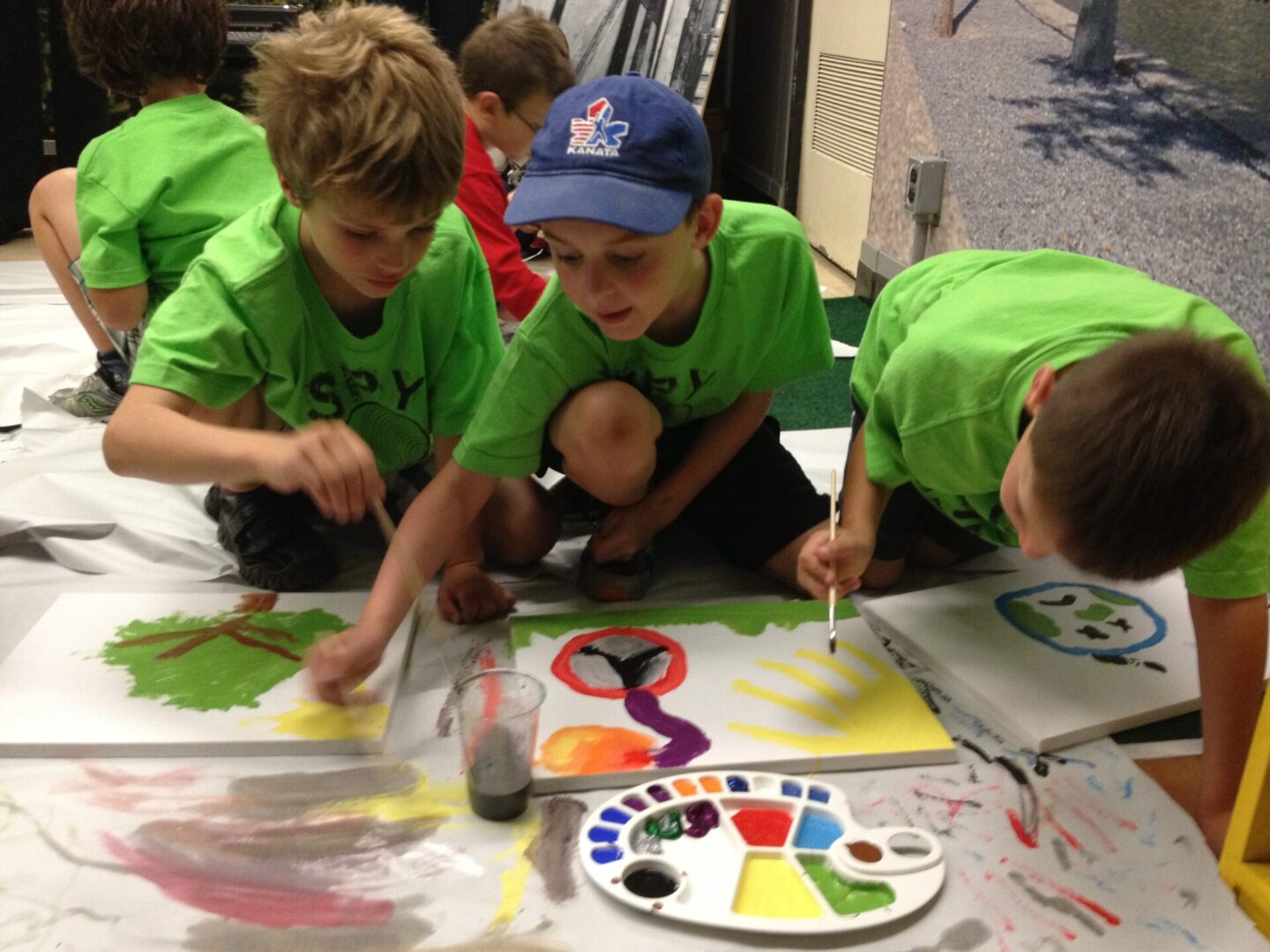 Children painting together on a large sheet with colorful paint.