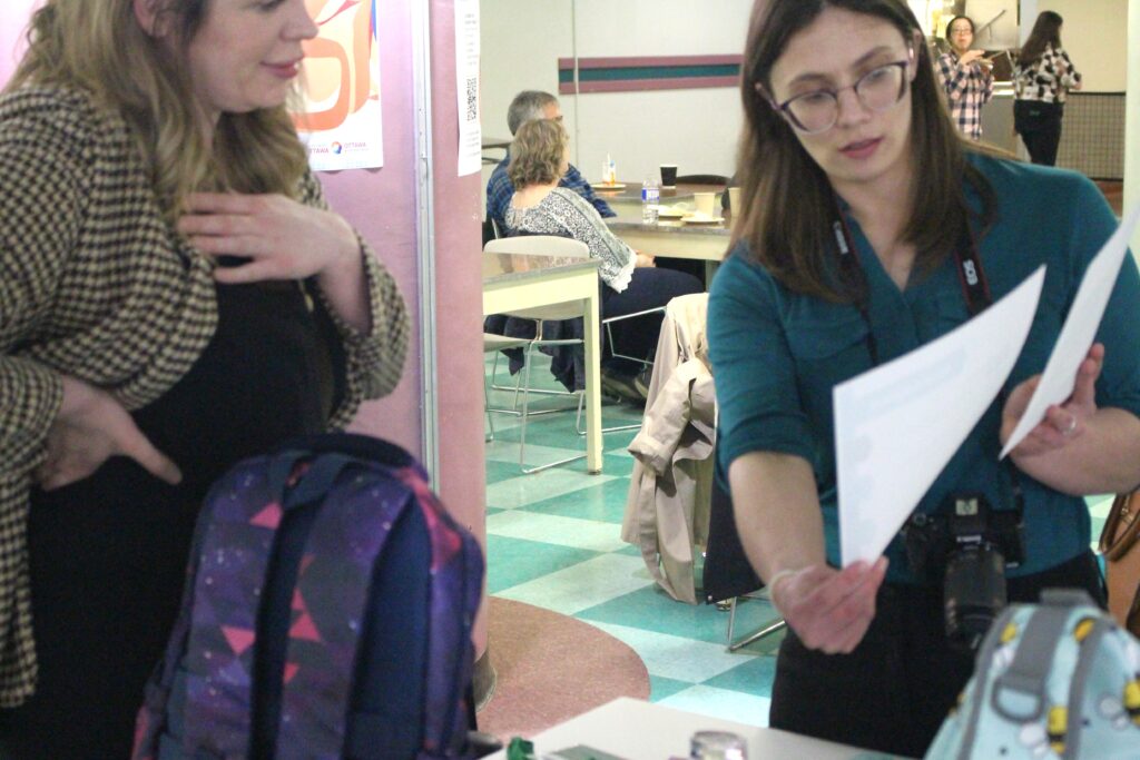 A person points out information on a piece of paper for a visitor.