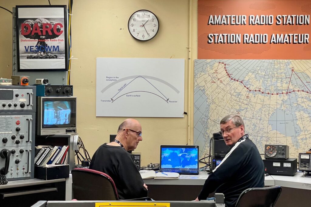 Volunteers sit in front of radio equipment at the Diefenbunker.