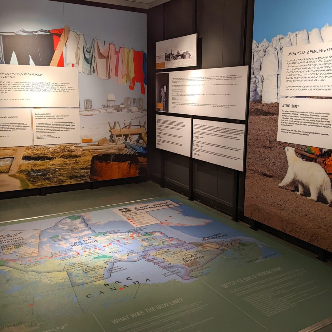 Colourful panels and images within an exhibition, including a large map of Canada on the floor.