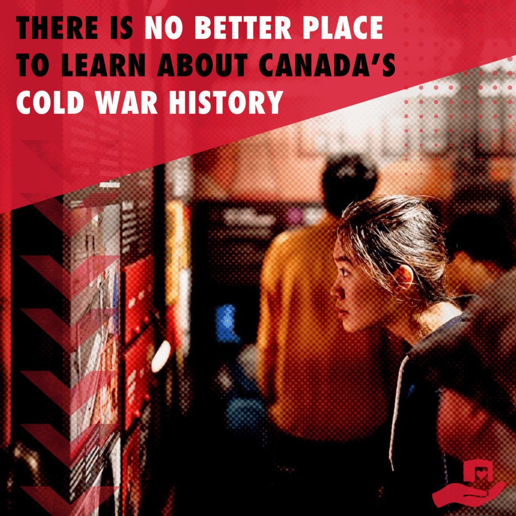 A woman stares intently at an information panel in a museum exhibition about propaganda, with graphic text at the top saying "There is no better place to learn about Canada's Cold War history".