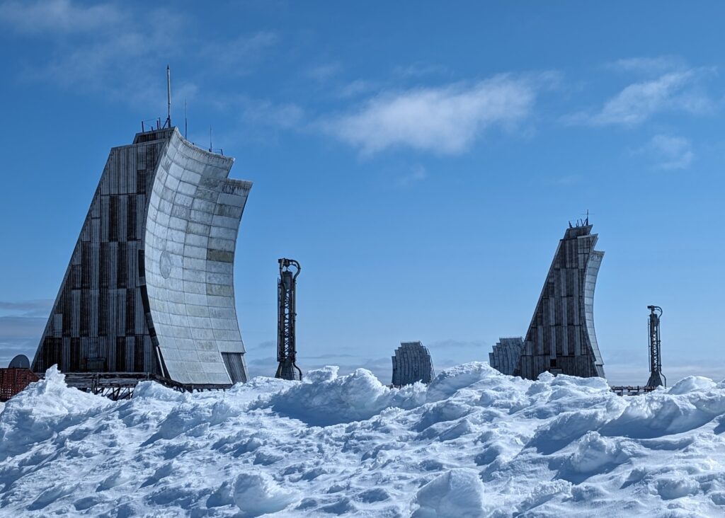 Two large grey parabolic antennae set in a snow-covered area.