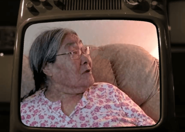 An Inuit woman sitting on a couch speaks in a testimonial.